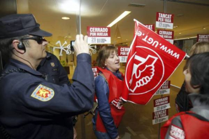 Un policía graba a los piquetes de los sindicatos CCOO y UGT en una oficina de Bankia. Foto: MIGUEL LORENZO