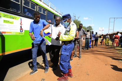 Un policía de Harare, Zimbabwe, comprueba los permisos para viajar de los pasajeros. AARON UFUMELI