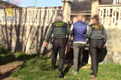 Dos agentes de la Guardia Civil con uno de los detenidos en una vivienda registrada. GUARDIA CIVIL