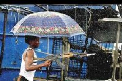 Una de las imágenes premiadas de Nick Bothma que muestra a un rebelde liberiano ante una casa acribillada a balazos. Está tomada en Monrovia.