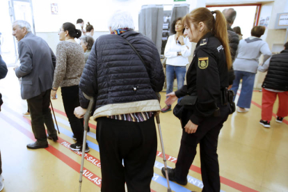 Una agente de policía ayuda a una mujer en un colegio electoral de León para que ejerza su derecho al voto. RAMIRO