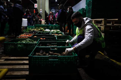 Un trabajador coloca jaulas de frutas y verduras en un mercado central para su distribución. JUAN IGNACIO RONCORONI