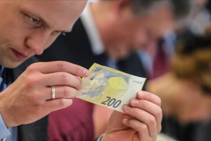 Un periodista inspecciona un nuevo billete de 200 euros, presentados este lunes.