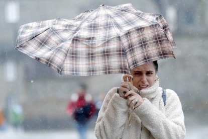 Una mujer se protege de la lluvia y el viento con un paraguas. LAVANDEIRA JR