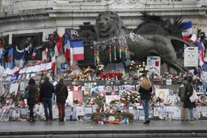 Homenajes a las víctimas en varios puntos de París. Sobre estas líneas, la placa conmemorativa en las antiguas oficinas de 'Charlie Hebdo'. A la derecha, un lector del último número de la revista en Niza.
