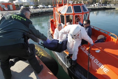 Agentes de la Guardia Civil y de Salvamento Maritimo trasladan el cadáver de uno de los inmigrantes fallecidos en aguas del Estrecho.