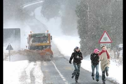 Tres jóvenes corren por la N-120 delante de un camión quitanieves que intenta despejar de nieve una de las zonas mas afectadas por el temporal, que ha castigado duramente a la comunidad navarra.