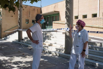 Dos sanitarios conversan en las inmediaciones del polideportivo Cortes de Aragón de Fraga, Huesca este martes donde se encuentran algunos enfermos con coronavirus. JAVIER BLASCO