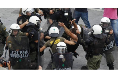 Policías golpean a un manifestante durante la manifestación de Atenas.