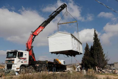 Una grúa levanta, ayer, una casa prefabricada del asentamiento de Amona, desmantelado por Israel.