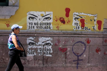 Una mujer pasa por una calle con carteles contra la violencia sexual. GUSTAVO AMADOR