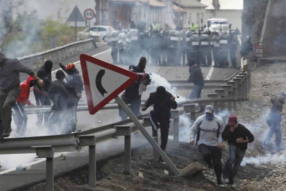 Los mineros corren al caer los botes de humo lanzados por los antidisturbios, a la entrada de Ciñera.