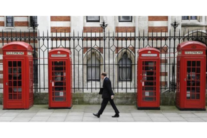 Un peaton anda ante varias de las icónicas cabinas rojas de British Telecom, en Londres.