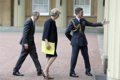La conservadora, Theresa May (c), y su marido, Philip John (i), a su llegada al palacio de Buckingham para recibir el mandato de la reina Isabel II para formar gobierno.