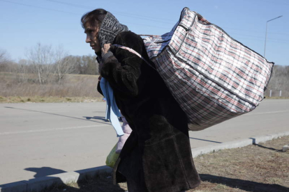 Una mujer ucraniana camina por la carretera con sus pertenencias en una bolsa. AMEL PAIN