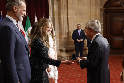 La princesa Leonor entrega al presidente del Comité Olímpico Internacional, Thomas Bach (d), Premio Princesa de Asturias de los Deportes, una insignia ante el rey Felipe, este viernes. EFE / BALLESTEROS