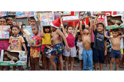 Niños posan para una fotografía con los regalos que recibieron para celebrar una Navidad. SEBASTIAO MOREIRA