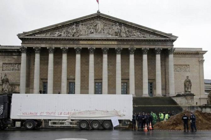 Agentes franceses permanecen junto al camión que ha vertido su carga de estiércol, esta mañana en París.