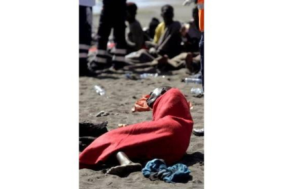 Unos inmigrantes descansan arropados en la playa de El Confital