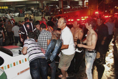 Un grupo de personas trasladan a una víctima del incendio de la discoteca Kiss, en Santa Maria (Brasil) este domingo.