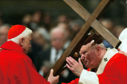 El Papa Juan Pablo II besa el crucifijo de madera que sostiene el cardenal Joseph Ratzinger  durante la Misa de la Pasión del Viernes Santo, en la Basílica de San Pedro, en el Vaticano, el 9 de abril de 2004. Un año después sería nombrado líder de la Iglesia católica. EFE/EPA/MAURIZIO BRAMBATTI