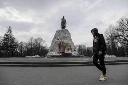 Un joven pasa ante la estatua dedicada al poeta ucraniano Taras Sevchenko, portegida por sacos terreros, en el parque del mismo nombre de la ciudad de Jarkiv. MANUEL BRUQUE