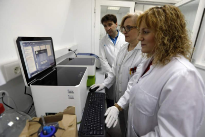 Emiliano Honrado, Engracia Santín y Cristina Díez, delante de uno de los aparatos que se utilizan para los análisis de biopsia líquida.