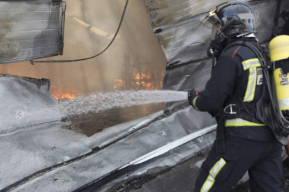 Un bombero del Ayuntamiento de León sofoca un incendio en una nave de Valverde de la Virgen. MARCIANO PÉREZ