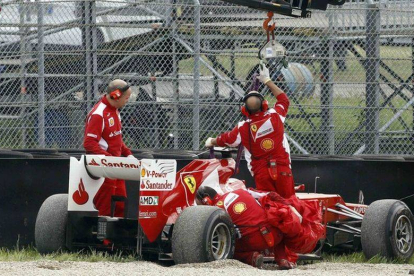 Operarios de Ferrari preparan el coche de Alonso para que sea remolcado feura de pista, en Mugello, Italia.