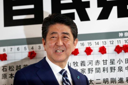 Abe sonríe mientras se dispone a colocar una rosa sobre el nombre de un candidato elegido para la Cámara baja, en la sede de su partido, en Tokio, el 22 de octubre.