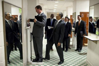 Marvin Nicholson, director de viajes del presidente, se pesa en una báscula mientras Obama bromea con él, en agosto del 2010. PETE SOUZA/ White House Photo Office