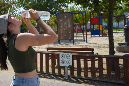 Una joven bebe agua en un parque de Lérida. RAMÓN GABRIEL
