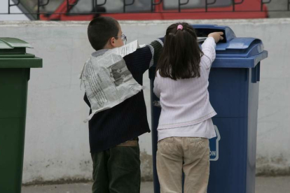 Dos escolares aprenden el uso de los contenedores de colores.