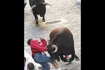 Uno de los toros voltea a un mozo al final de la cuesta de Santo Domingo, aunque por suerte no llegó a cornearlo.
