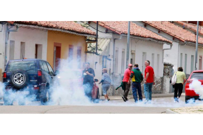 Vecinos y mineros huyen tras el lanzamiento de un bote de humo por parte de los antidisturbios en las calles de Ciñera.