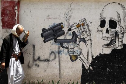 Un hombre camina junto a un grafiti antitabaco en Saná (Yemen).  YAHYA ARHAB