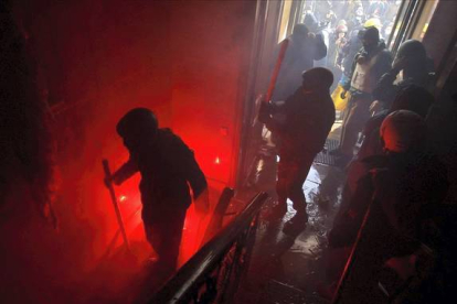 Manifestantes armados con palos entran en el interior de un edificio próximo al Parlamento.