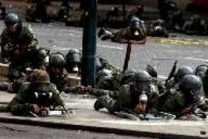 Guardias nacionales venezolanos se cubren de los disparos de los opositores en Caracas
