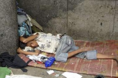 Un niño sin hogar dormita en un rincón de Phnom Penh, Camboya, al amanecer.
