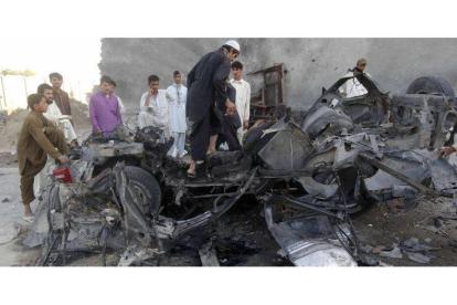 Afganos alrededor de los restos de un choche utilizado por un terrorista suicida.