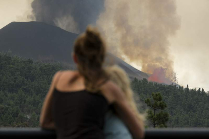 Una mujer abraza a su hija mientras contemplan el volcán en La Palma. ÁNGEL MEDINA