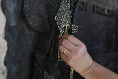 Un mujer tira de la nariz a San Froilán en la escultura que Subirachs hizo del patrón de la Díocesis de León en la fachada sur del santuario de La Virgen del Camino. RAMIRO