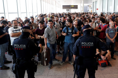 Agentes de los Mossos d'Esquadra y de la Policía Nacional controlan el acceso de personas a la terminal 1 del Aeropuerto de El Prat. ALEJANDRO GARCÍA.