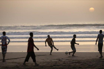 Jóvenes marroquíes jugando a fútbol en la playa de Agadir, al sur del país.