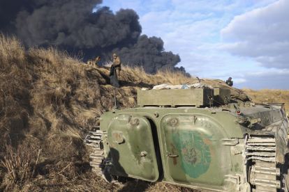 Los militares ucranianos descansan en una posición mirando el humo de un depósito de almacenamiento de petróleo quemado detrás después de que un misil ruso atacara cerca de Kiev. ALISA YAKUBOVYCH - EFE