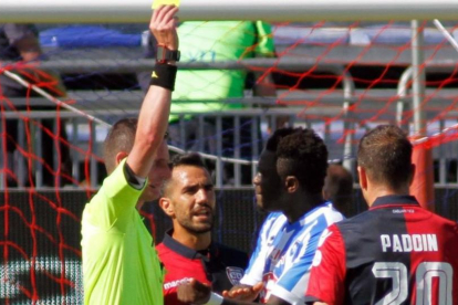 El árbitro Daniele Minelli saca la tarjeta amarilla a Muntari durante el Cagliari-Pescara del domingo.