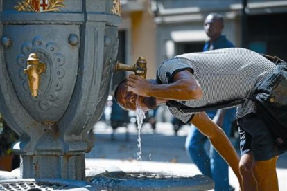 Un joven bebe agua en una fuente pública de Barcelona.