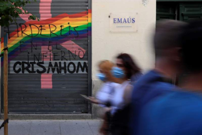 Varias personas pasan delante de una pintada contra el movimiento LGTBI en Chueca, ayer. FERNANDO ALVARADO