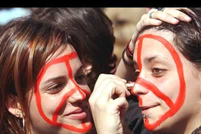 Dos jovenes se pintan la cara con el símbolo de la paz al comienzo de la manifestación en la que miles de estudiantes de la Universidad Autónoma de Barcelona cortaron la autopista A-7.