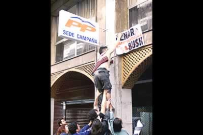 Un grupo de estudiantes colocan una pancarta contra la guerra en Irak en la sede del PP en Granada, tras la manifestación que reunió en esta ciudad a miles de ciudadanos en protesta por el conflicto bélico.